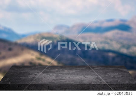 Black stone surface on background of highlands with blue sky. Black stone surface on background of highlands with blue sky. 62043035