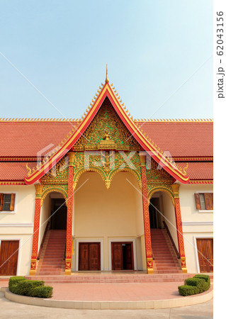An entrance of Buddhist temple with ornate red roof in Vientiane in Laos against blue sky An entrance of Buddhist temple with ornate red roof in Vientiane in Laos against blue sky 62043156