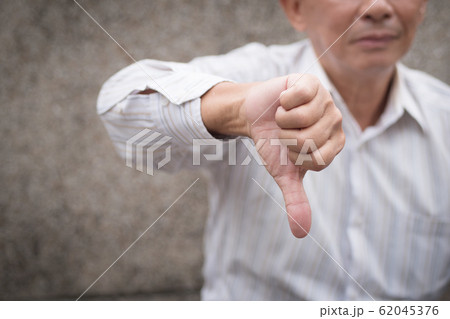 angry senior giving thumb down gesture, unhappy 62045376