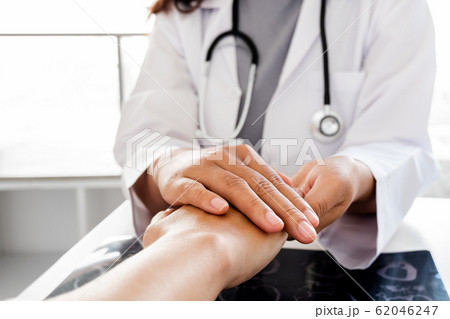 The female doctor uses a friendly hand to hold the hand of the patient to give confidence after the x-ray and advise on health care. Medical concepts and good health The female doctor uses a friendly hand to hold the hand of the patient to give confidence after the x-ray and advise on health care. Medical concepts and good health 62046247
