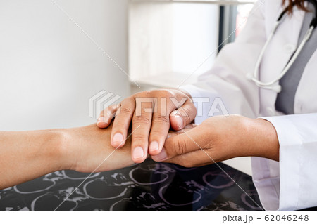 The female doctor uses a friendly hand to hold the hand of the patient to give confidence after the x-ray and advise on health care. Medical concepts and good health The female doctor uses a friendly hand to hold the hand of the patient to give confidence after the x-ray and advise on health care. Medical concepts and good health 62046248