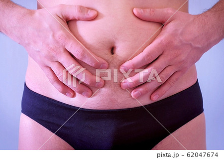 Man in underpants touches his flabby fat naked stomach, closeup view. Man in underpants touches his flabby fat naked stomach, closeup view. 62047674