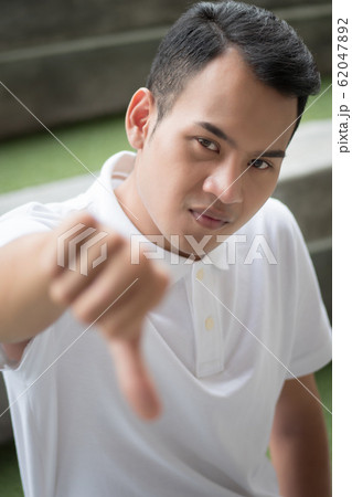 rejecting man showing thumb down gesture; man rejecting man showing thumb down gesture; man 62047892