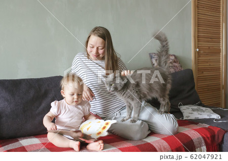 Young caucasian beautiful mother sitting on a couch at home in casual clothes watching sweet baby Young caucasian beautiful mother sitting on a couch at home in casual clothes watching sweet baby 62047921