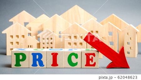 Wooden blocks with the word Price, down arrow and wooden houses. The concept of low cost real estate. Lower mortgage interest rates. Falling prices for rental housing and apartments. Wooden blocks with the word Price, down arrow and wooden houses. The concept of low cost real estate. Lower mortgage interest rates. Falling prices for rental housing and apartments. 62048623