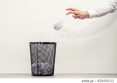 Businessman throwing waste paper to trash can in office 62050211