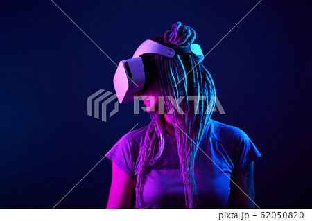 Woman is using virtual reality headset. Neon light studio portrait. 62050820