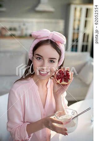 Young pretty girl in a pink headband showing a pomegranate 62052554