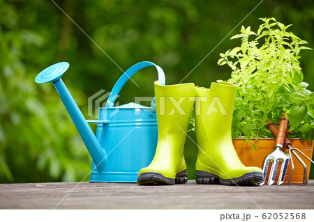 Rubber boots with watering can in wood terrace Rubber boots with watering can in wood terrace 62052568