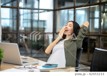 Long-haired brunette asian girl feeling tired and yawning 62053233