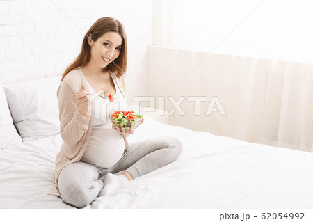 Pregnant woman eating natural vegetable salad in bed 62054992