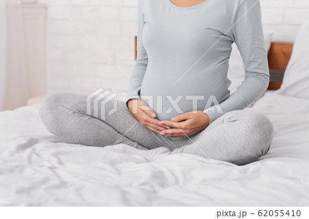 Unrecognizable Pregnant Woman Touching Her Belly Sitting In Bed 62055410