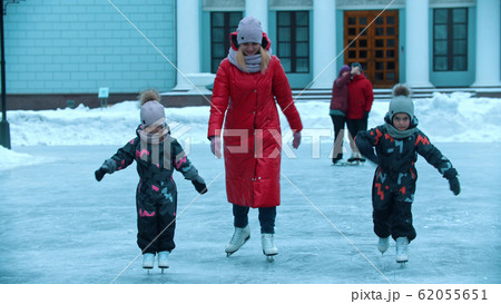 A young woman skating on ice with her children 62055651