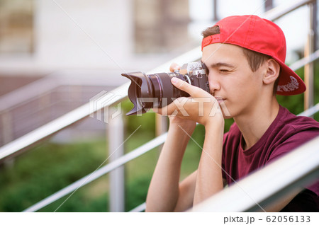 Teenage boy taking photos outdoors. Young man Teenage boy taking photos outdoors. Young man 62056133