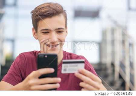 Teenage boy with a credit card and mobile phone 62056139