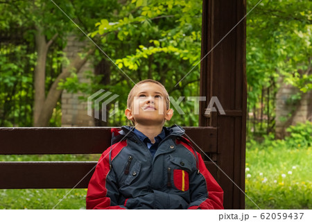 Teenager is looking up while sitting on bench 62059437