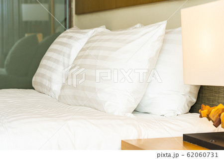 White comfortable pillow on bed decoration with light lamp White comfortable pillow on bed decoration with light lamp 62060731
