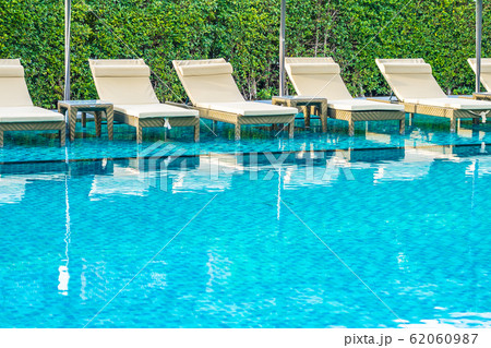 Umbrella and chair sofa around outdoor swimming pool in hotel resort for holiday vacation Umbrella and chair sofa around outdoor swimming pool in hotel resort for holiday vacation 62060987