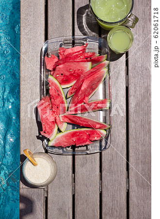 Watermelon plate and summer dkinks near pool. Exotic summer diet. Tropical beach lifestyle. 62061718