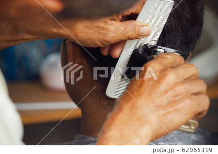 Closeup hand of hairdresser cutting hair with clipper at local barber shop. 62065319