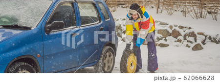 Winter accident on the road. A man changes a wheel during a snowfall. Winter problems BANNER, LONG 62066628