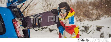 The snowboard does not fit into the car. A snowboarder is trying to stick a snowboard into a car The snowboard does not fit into the car. A snowboarder is trying to stick a snowboard into a car 62066908