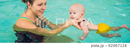 Beautiful mother teaching cute baby girl how to swim in a swimming pool. Child having fun in water Beautiful mother teaching cute baby girl how to swim in a swimming pool. Child having fun in water 62067128