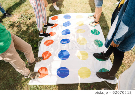 Children playing a twister on the grass. Legs on red. Children playing a twister on the grass. Legs on red. 62070512