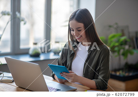 Nice joyful girl with a tablet in her hands. Nice joyful girl with a tablet in her hands. 62072799