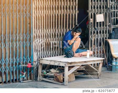 A middle-aged woman is sitting and pulling her gray hair with tweezers and a mirror by herself in front of her house during her free time. A middle-aged woman is sitting and pulling her gray hair with tweezers and a mirror by herself in front of her house during her free time. 62075877