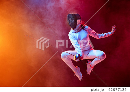 Teen girl in fencing costume with sword in hand isolated on black background 62077125