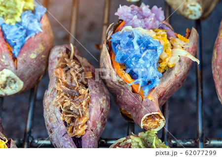 Colorful of many Thai traditional desserts stuffed in grilled yams on stove for sale on street food. Colorful of many Thai traditional desserts stuffed in grilled yams on stove for sale on street food. 62077299