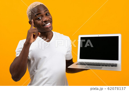 african man with white hair smiling holding laptop screen forward with mock up on yellow background african man with white hair smiling holding laptop screen forward with mock up on yellow background 62078137