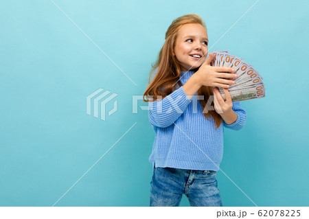 Portrait of little caucasian girl with long brow hair in blue hoody holds a lot of money isolated on 62078225