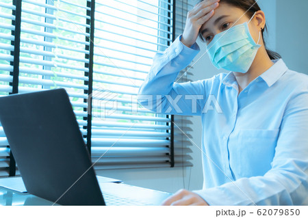 woman headache with face mask protection while working, Coronavirus, air pollution, allergic sick 62079850