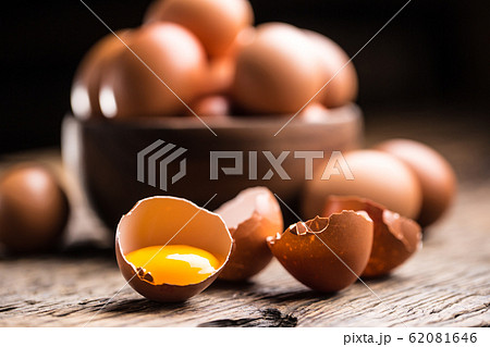 Broken chicken eggs with yolk on wooden table 62081646