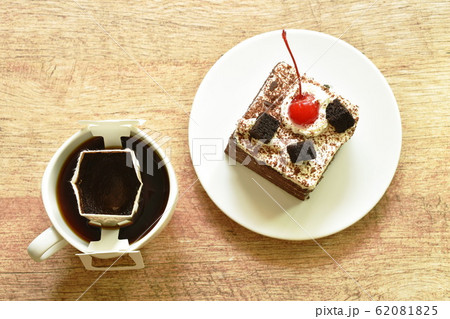 black fotest cake with cream topping cherry and hot coffee drip filter in cup black fotest cake with cream topping cherry and hot coffee drip filter in cup 62081825