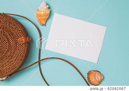 Seashells and ratan bag on blue background, top view. 62082067