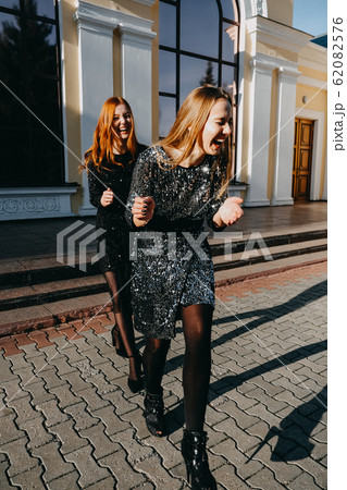 Evening party cocktail outfit ideas. What to wear. Trend and fashion. Two Beautiful stunning young women in glitter sequins dress outdoor. Blonde and redhair girl in cocktail dresses lifestyle Evening party cocktail outfit ideas. What to wear. Trend and fashion. Two Beautiful stunning young women in glitter sequins dress outdoor. Blonde and redhair girl in cocktail dresses lifestyle 62082576