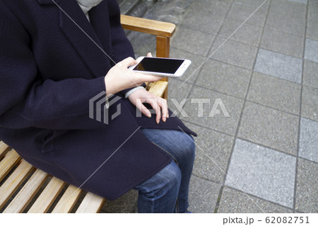 ベンチに座りスマホを操作する女性 62082751