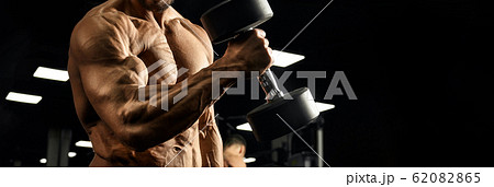 Male bodybuilder training biceps with dumbbell. Male bodybuilder training biceps with dumbbell. 62082865
