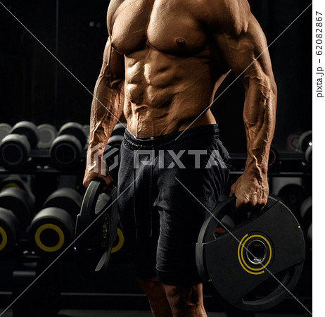 Male bodybuilder holding weights. 62082867