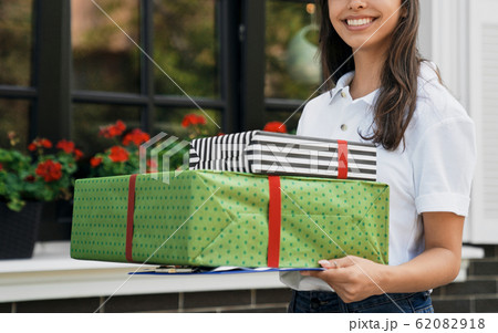 Female courier holding gift boxes and folder. 62082918