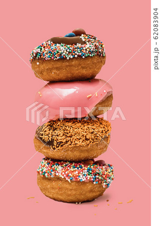 Donuts one on each other with icing and chocolate on pink background. Sweet donuts Donuts one on each other with icing and chocolate on pink background. Sweet donuts 62083904