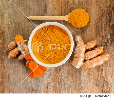 Turmeric roots with turmeric powder on wooden Turmeric roots with turmeric powder on wooden 62085021