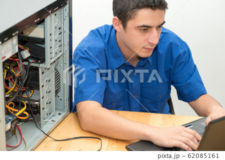 Young technician working on broken computer in his 62085161