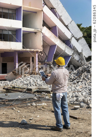 Engineer holding tablet is checking for destruction, demolishing building. Engineer holding tablet is checking for destruction, demolishing building. 62086345