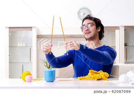Young good looking man knitting at home Young good looking man knitting at home 62087099