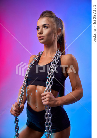 Muscular woman holding chains on neck. Muscular woman holding chains on neck. 62087351