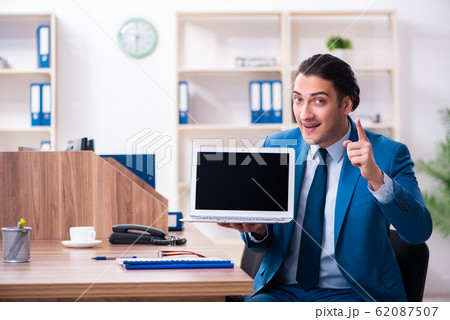 Young handsome businessman sitting in the office Young handsome businessman sitting in the office 62087507